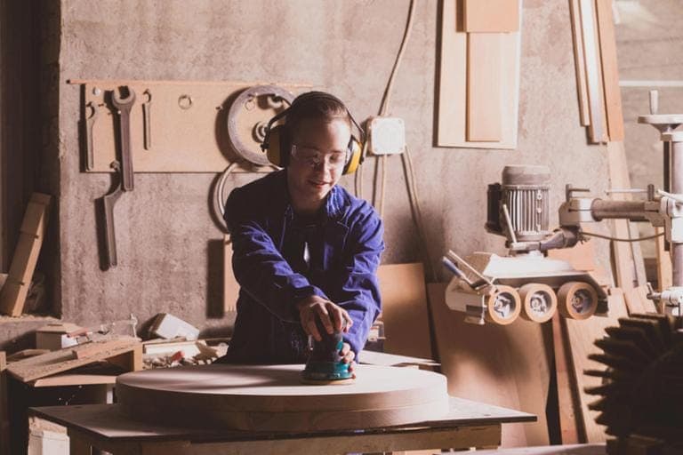 36662184-tischlerin-werkstatt-poliert-holzplatte-blauen-overall-Oa73